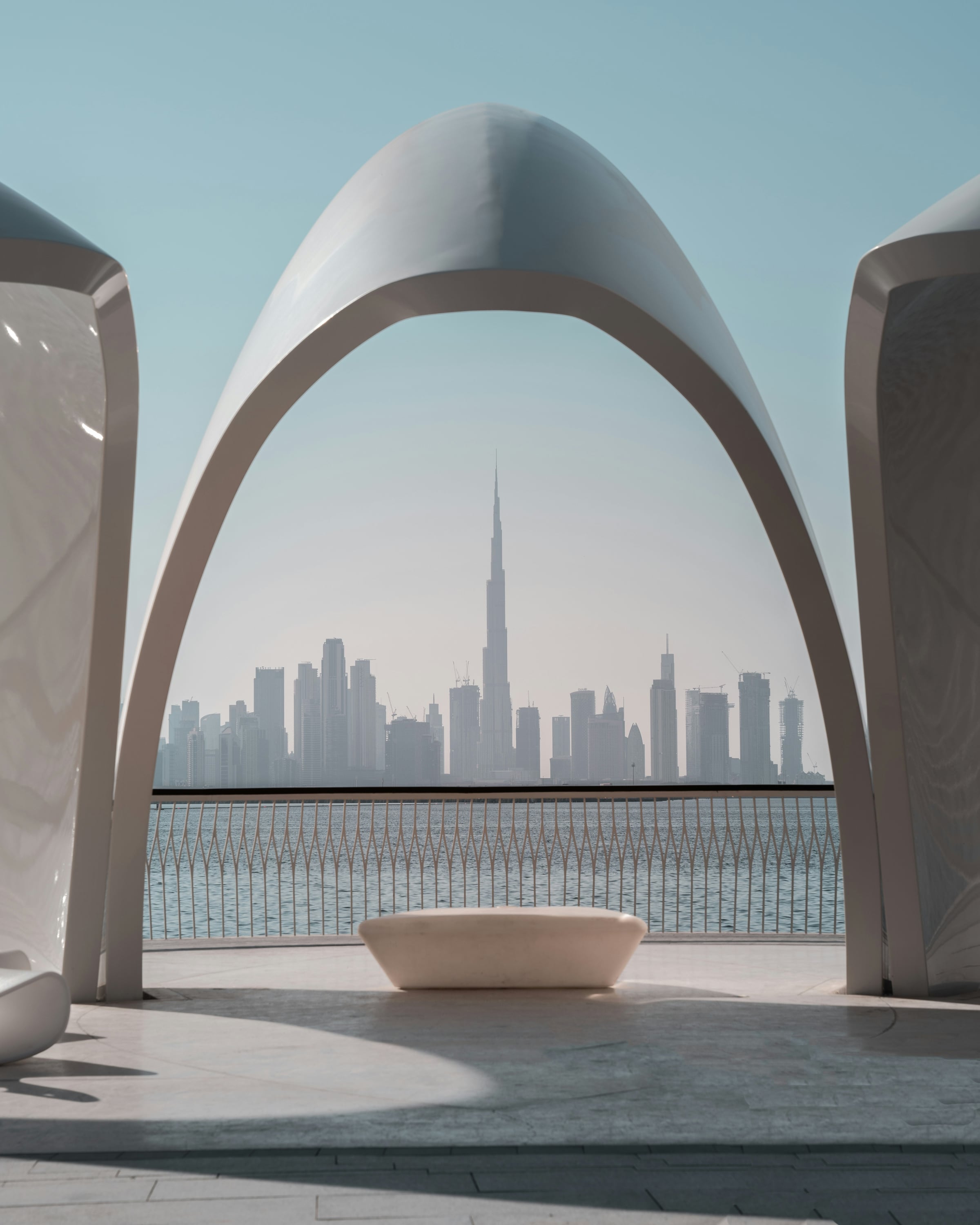 A white arch framing the Dubai skyline across the creek