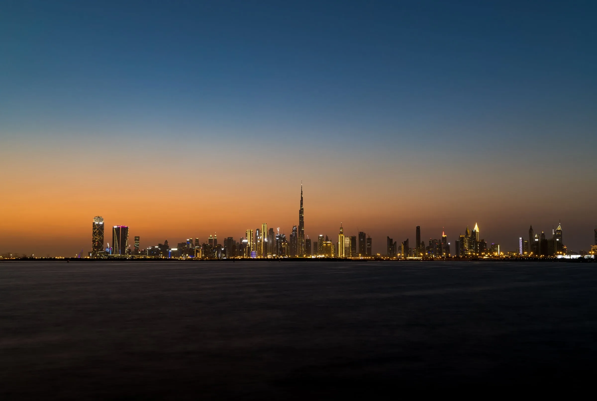 Dubai skyline across calm water at dusk